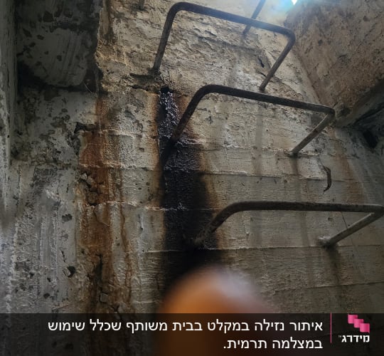 סולם מתכת חלוד על קיר בטון עם סימני נזילה